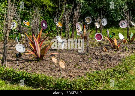 Plaques sur poteaux dans un jardin avant en France, Nouvelle-Aquitaine. Le motif correspond au proverbe allemand 'Über den Tellerrand schauen' (regardez au-delà du bord de votre assiette), qui fait référence à une attitude ouverte et curieuse dans laquelle on est prêt à transcender ses propres frontières et à apprendre de nouvelles choses. La phrase est souvent utilisée en relation avec le cosmopolitisme, un changement de perspective ou une innovation. Penser hors de la boîte. L'installation décorative de jardin comprend différentes pièces de vaisselle attachées à des bâtons et placées dans un parterre de fleurs pour créer une scène ludique et artistique. L'installation est Banque D'Images