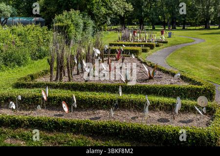 Plaques sur poteaux dans un jardin avant en France, Nouvelle-Aquitaine. Le motif correspond au proverbe allemand 'Über den Tellerrand schauen' (regardez au-delà du bord de votre assiette), qui fait référence à une attitude ouverte et curieuse dans laquelle on est prêt à transcender ses propres frontières et à apprendre de nouvelles choses. La phrase est souvent utilisée en relation avec le cosmopolitisme, un changement de perspective ou une innovation. Penser hors de la boîte. L'installation décorative de jardin comprend différentes pièces de vaisselle attachées à des bâtons et placées dans un parterre de fleurs pour créer une scène ludique et artistique. L'installation est Banque D'Images