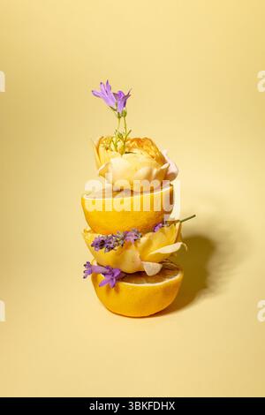 Composition créative faite de tranches de citron, fleur jaune et violette sur fond beige. Nature morte Banque D'Images