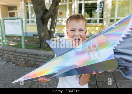 Smiling Boy tient Schultuete coloré en forme de requin rempli de cadeaux lors de son premier jour d'école en Allemagne. Cône brillant avec des ailerons et des yeux symbolise Banque D'Images