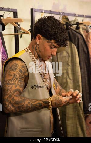 News - PDF - célébrités et coulisses - Milan Fashion week - homme printemps/été 2026 Tony Effe prépare une cigarette au défilé PDF dans les coulisses de la Milan Menswear printemps/été 2026 Fashion week le 20 juin 2025 à Milan, Italie. Photo : Cinzia Camela. MILAN Caserma XXIV Maggio Italie Copyright : xCinziaxCamelax/xLiveMediax LPN 1930846 Banque D'Images