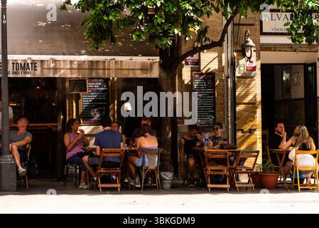 Sevilla, Espagne-15 juin 2025 : les gens sont assis à l'ombre dans un café dans le quartier Santa Cruz de Séville. Banque D'Images