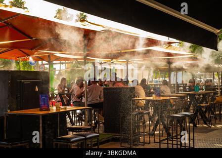 Sevilla, Espagne-15 juin 2025 : les gens sont assis à l'ombre dans un café avec de la brume d'eau pulvérisée de l'auvent pour refroidir les gens dans la chaleur intense de la ville Banque D'Images