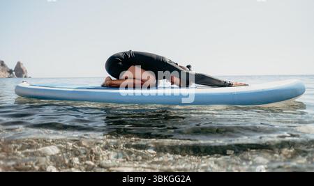 Yoga Paddleboard Water Man faisant du yoga sur paddleboard dans l'océan. Banque D'Images