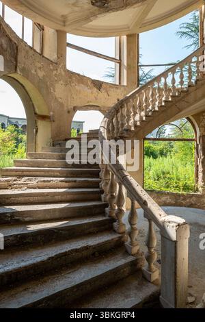 Escalier en spirale délabré dans un bâtiment abandonné avec végétation envahie à Tskaltubo, Géorgie Banque D'Images