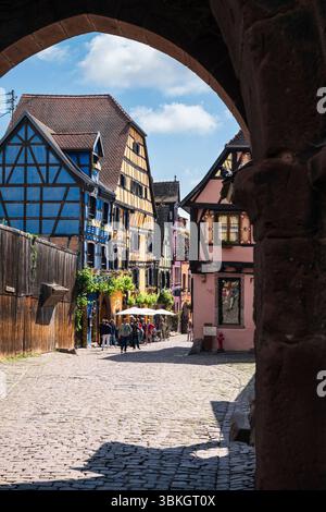 Vue à travers la porte supérieure de la ville de la tour de guet Dolder jusqu'aux maisons à colombages dans le vieux centre-ville de Riquewihr, Alsace, France Banque D'Images