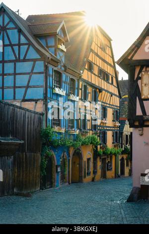 Le soleil radieux se lève sur les maisons colorées à colombages dans la vieille ville de Riquewihr, Alsace, France Banque D'Images