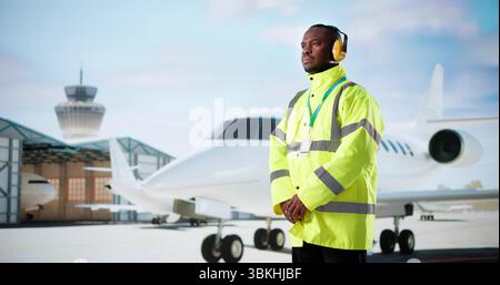 Ingénieur afro-américain de maintenance aéronautique en uniforme jaune travaillant sur avion Banque D'Images