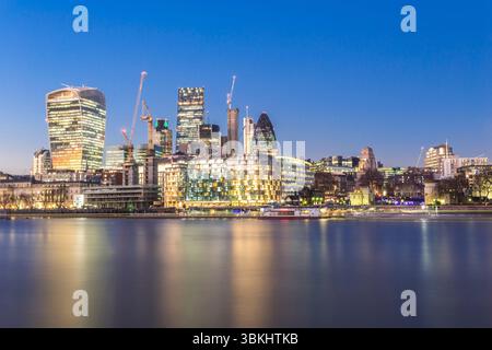 La ligne d'horizon moderne de Londres majestueusement illuminée au crépuscule avec un superbe reflet de la rivière Banque D'Images