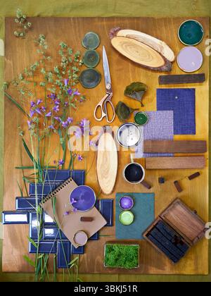 Pose à plat d'une composition créative de moodboard avec des matériaux naturels, des échantillons de tissu, des herbes forestières, des textures en bois et une palette de couleurs aux tons verts Banque D'Images