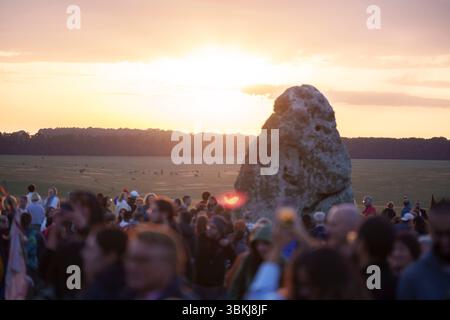 Les fêtards spirituels regardent le soleil levant sur la pierre du talon et célèbrent le solstice d'été (mi-été et jour le plus long) parmi les anciennes pierres du néolithique tardif de Stonehenge, le 21 juin 2025, dans le Wiltshire, en Angleterre. Le solstice d'été est le jour le plus long de l'hémisphère nord et la nuit la plus courte de l'année, lorsque l'axe de la terre est incliné à son point le plus proche du soleil et les païens disent que l'ancien monument est un lieu sacré qui relie la Terre, la Lune, le Soleil et les saisons. Stonehenge a été construit en trois phases entre 3 000 av. J.-C. et 1 600 av. J.-C. et est maintenant la propriété de English Heritage qui disent 2 Banque D'Images