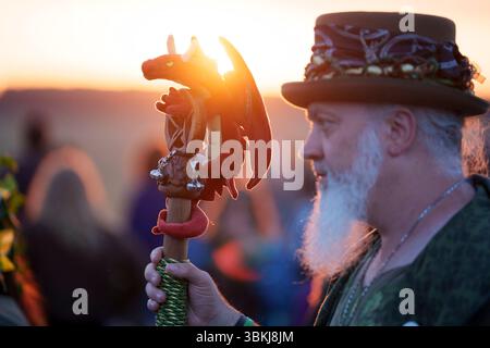 Les fêtards spirituels regardent le soleil levant et célèbrent le solstice d'été (mi-été et jour le plus long) parmi les anciennes pierres du néolithique tardif de Stonehenge, le 21 juin 2025, dans le Wiltshire, en Angleterre. Le solstice d'été est le jour le plus long de l'hémisphère nord et la nuit la plus courte de l'année, lorsque l'axe de la terre est incliné à son point le plus proche du soleil et les païens disent que l'ancien monument est un lieu sacré qui relie la Terre, la Lune, le Soleil et les saisons. Stonehenge a été construit en trois phases entre 3 000 av. J.-C. et 1 600 av. J.-C. et est maintenant la propriété de English Heritage qui dit que 25 000 visiteurs étaient Banque D'Images