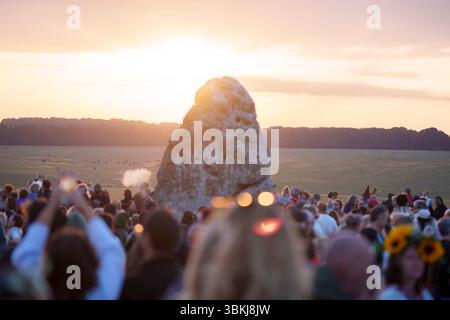 Les fêtards spirituels regardent le soleil levant sur la pierre du talon et célèbrent le solstice d'été (mi-été et jour le plus long) parmi les anciennes pierres du néolithique tardif de Stonehenge, le 21 juin 2025, dans le Wiltshire, en Angleterre. Le solstice d'été est le jour le plus long de l'hémisphère nord et la nuit la plus courte de l'année, lorsque l'axe de la terre est incliné à son point le plus proche du soleil et les païens disent que l'ancien monument est un lieu sacré qui relie la Terre, la Lune, le Soleil et les saisons. Stonehenge a été construit en trois phases entre 3 000 av. J.-C. et 1 600 av. J.-C. et est maintenant la propriété de English Heritage qui disent 2 Banque D'Images