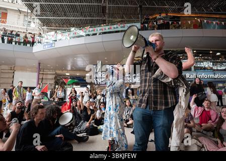 Londres, Royaume-Uni. 21 juin 2025. Les activistes de Youth Demand occupent brièvement le hall de la gare de Waterloo, exigeant « pas de guerre contre l'Iran » et soulignant le sort du peuple palestinien, dépliant les passagers qui passent et appelant le gouvernement britannique à cesser d'armer, de former et de soutenir Israël. Le gouvernement israélien fait actuellement l’objet d’une enquête sur des allégations de génocide pour sa conduite à Gaza, tandis que le leader Benjamin Netanyahu est recherché par la Cour pénale internationale pour crimes de guerre et crimes contre l’humanité. Crédit : Ron Fassbender/Alamy Live News Banque D'Images