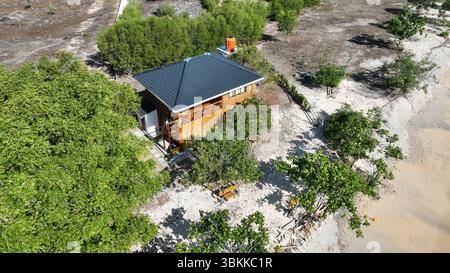 Cette charmante maison en bois sur l'île Gede offre une escapade tranquille, nichée entre les arbres ombragés et les vagues douces d'une plage de sable immaculée. Banque D'Images