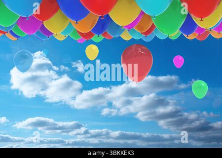 Conception plate montrant des ballons en latex multicolores en grappe dérivant à travers le ciel bleu parsemé de nuages Banque D'Images