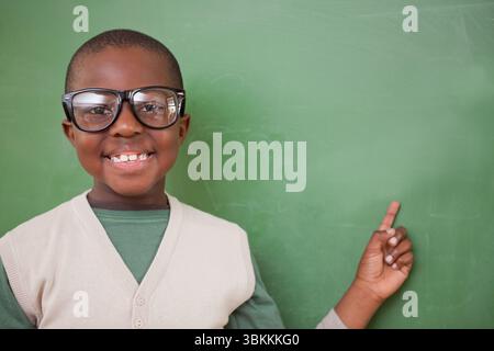 Garçon pointe vers le tableau dans la scène de classe de design plat avec des lunettes noires et gilet beige Banque D'Images
