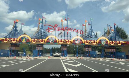 Une vue frontale de l'entrée de Disneyland Paris. La structure est décorée de personnages Disney et de drapeaux aux couleurs vives sous un ciel nuageux. Banque D'Images