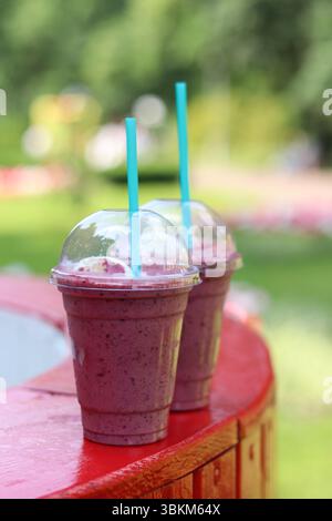 Milkshake aux baies avec de la crème glacée. Boisson d'été dans une tasse en plastique jetable avec paille. Café avec crème glacée et sirop de baies. Boisson rafraîchissante en été d Banque D'Images