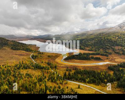 Une vue aérienne du lac Yazovoe situé dans une vallée d'automne, avec une rivière sinueuse qui coule à travers des champs dorés et des forêts Banque D'Images