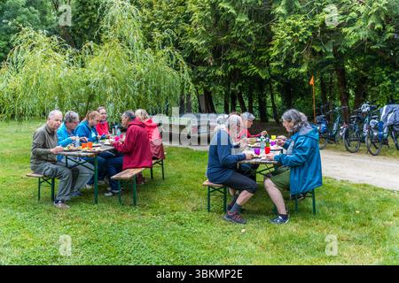 Pique-nique d'un groupe de balades à vélo au départ de Die Landpartie sur les rives de la Charente. Un groupe de cyclistes se sont rassemblés pour un pique-nique. Ils sont assis à des tables et des bancs, appréciant leur nourriture et l'entreprise à l'extérieur. Chemin de l'Ecluse, Saint-Yrieix-sur-Charente, Nouvelle-Aquitaine, France Banque D'Images