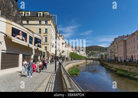 Rue commerçante avec des touristes le long des rives de la rivière Tepla à Karlovy Vary en République tchèque Banque D'Images