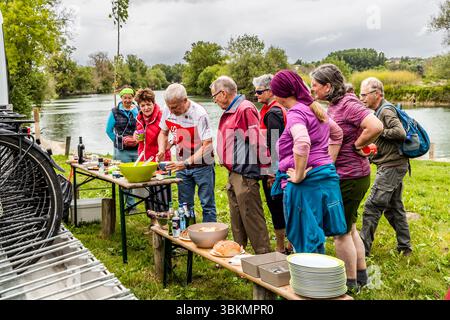 Pique-nique au bord d'une rivière. Après avoir pédalé ensemble, vous pourrez vous fortifier avec des spécialités régionales françaises. À mi-parcours de la journée, les participants à la balade à vélo organisée par Die Landpartie pourront profiter d'un pique-nique avec des spécialités locales du département de la Charente. Le Ponton, Rouffiac, Nouvelle-Aquitaine, France Banque D'Images