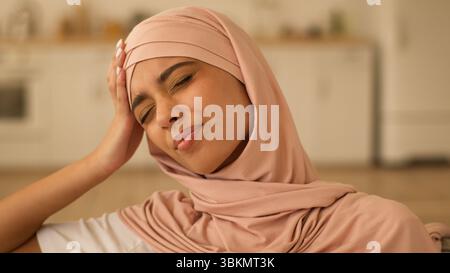 Portrait triste pensée frustré malade mauvais sentiment stress femme indienne fille arabe femme musulmane femme islamique femme islamique dans le hijab à la maison tenir la tête douloureuse Banque D'Images