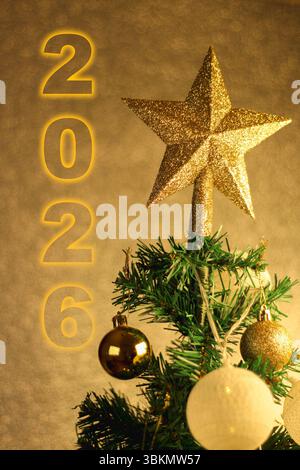 Gros plan d'un sapin de Noël avec une étoile sur le dessus, ornée de sphères et de lumières jaunes. Préparation pour célébrer l'idée de concept du nouvel an. 2026 Banque D'Images