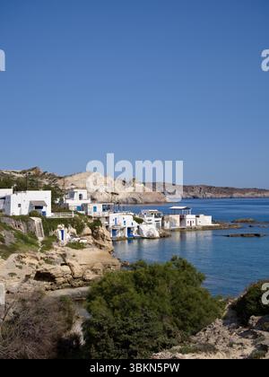 Vue lointaine sur un village côtier grec traditionnel sur l'île de Milos, avec des maisons blanchies à la chaux des Cyclades le long d'un rivage rocheux. Banque D'Images
