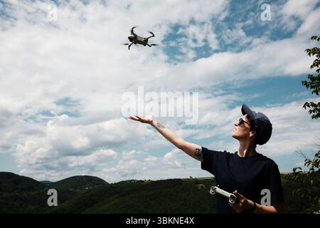 Femme volant un drone au-dessus du pittoresque lac Rovni en Serbie. Elle tend la main sous le drone et tient le contrôleur, souriant et profitant du sprin Banque D'Images