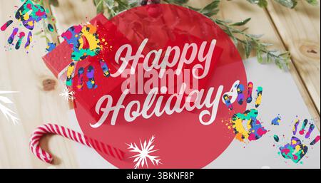 Montrant la bannière Happy Holidays sur une table, avec canne à bonbons, branche à feuilles persistantes, empreintes de mains, papier Banque D'Images