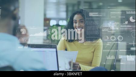 Femme dans le rapport d'analyse de dessus jaune avec des superpositions de données dans un bureau ouvert moderne, avec ordinateur portable Banque D'Images