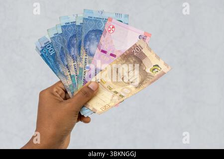 Monnaie rand sud-africaine en main féminine, y compris des billets de 20, 50 et 100 rand. Concept financier de richesse et d'économie. Banque D'Images