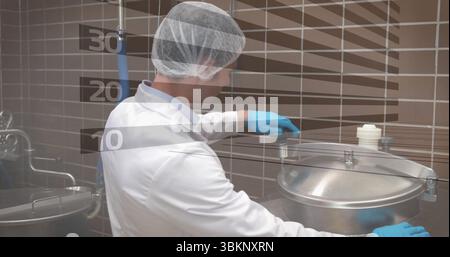 Technicien en blouse de laboratoire, gants, loquet de torsion de filet de cheveux sur le réservoir en acier inoxydable dans la cuisine, tuyaux Banque D'Images