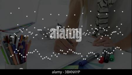 Femme écrivant portant une écharpe rayée au bureau, avec des graphiques imprimés et un stylo noir Banque D'Images