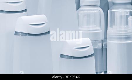 Rangée de bouteilles blanches avec couvercles sur eux. Certains sont étiquetés comme shampooing, certains comme revitalisant, et certains comme nettoyant corporel Banque D'Images