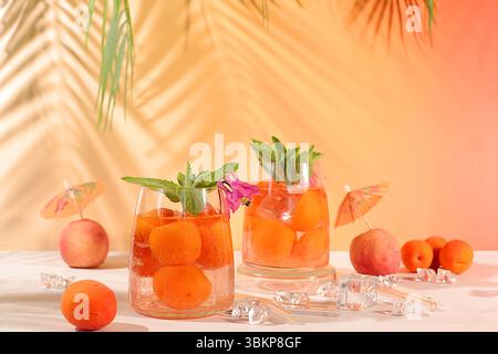 Thé de pêche glacé ou cocktail à la menthe et aux abricots, recette rafraîchissante de boisson estivale. Deux verres avec limonade aux fruits de pêche sur une table lumineuse, régime détox Banque D'Images