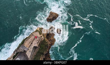Vue aérienne d'un vieux phare sur une falaise dans la ville de Nazare, Portugal. Banque D'Images
