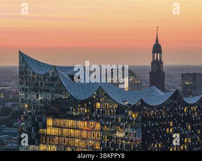 Vue aérienne de l'Elbphilharmonie au coucher du soleil avec fenêtres éclairées et vue sur Hambourg et l'église principale St Michaelis (Michel), Hambourg, allemand Banque D'Images