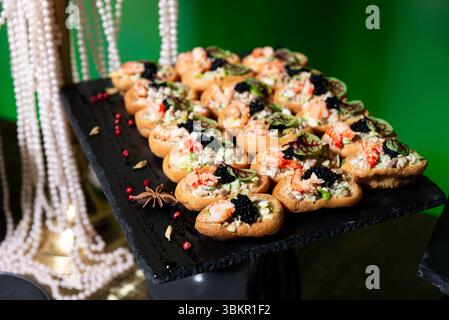 Canapés de fruits de mer élégants remplis de crevettes, mélange de salades et recouverts de caviar noir, parfaits pour les fêtes et réceptions haut de gamme. Banque D'Images
