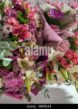 Arrangements floraux vibrants avec lys roses et blancs, roses, chrysanthèmes et orchidées, enveloppés dans du papier doux, idéal pour les mariages et les cadeaux. Banque D'Images