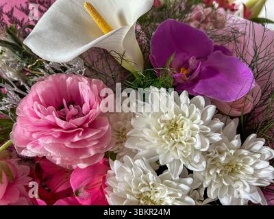 Gros plan d'un bouquet floral raffiné avec un lys calla blanc, une orchidée violette, un ranoncule rose et des chrysanthèmes blancs, parfaits pour les mariages, cel Banque D'Images