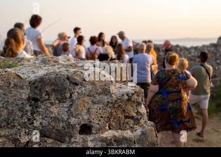 Touristes explorant les ruines antiques au coucher du soleil Banque D'Images