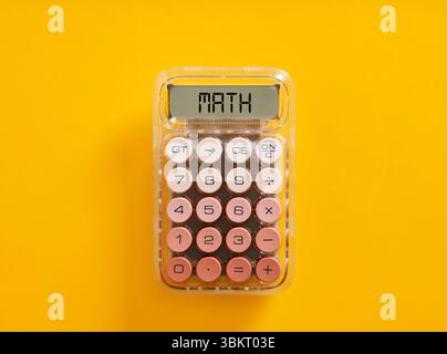 Calculatrice affichant le mot maths sur son écran est couché sur un fond jaune. Calculs mathématiques et concept d'éducation. Banque D'Images
