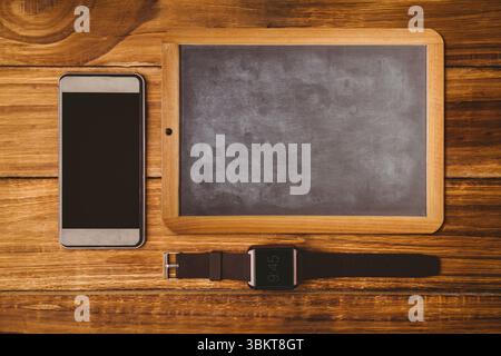 La conception plate montre smartphone haut-bas, tableau noir, smartwatch placé sur une table en bois rustique Banque D'Images