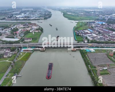 Suzhou. 23 juin 2025. Une photo prise par un drone aérien le 23 juin 2025 montre une vue du pont de Pingwang dans le district de Wujiang de la ville de Suzhou, dans la province du Jiangsu de l'est de la Chine. Les voies de gauche du pont de Pingwang nouvellement construit, un projet de la partie est du projet d'amélioration du canal de navigation de Chang-Hu-Shen (Changxin-Huzhou-Shanghai) (section Jiangsu), ont été officiellement ouvertes à la circulation lundi. Crédit : Ji Chunpeng/Xinhua/Alamy Live News Banque D'Images