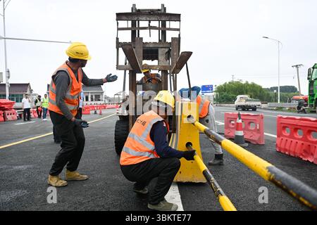 Suzhou. 23 juin 2025. Les ouvriers ont remis en place les séparateurs routiers pour les voies de gauche du pont de Pingwang nouvellement construit dans le district de Wujiang de la ville de Suzhou, dans la province du Jiangsu de l'est de la Chine, le 23 juin 2025. Les voies de gauche du pont de Pingwang nouvellement construit, un projet de la partie est du projet d'amélioration du canal de navigation de Chang-Hu-Shen (Changxin-Huzhou-Shanghai) (section Jiangsu), ont été officiellement ouvertes à la circulation lundi. Crédit : Ji Chunpeng/Xinhua/Alamy Live News Banque D'Images