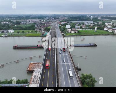 Suzhou. 23 juin 2025. Une photo prise par un drone aérien le 23 juin 2025 montre une vue du pont de Pingwang dans le district de Wujiang de la ville de Suzhou, dans la province du Jiangsu de l'est de la Chine. Les voies de gauche du pont de Pingwang nouvellement construit, un projet de la partie est du projet d'amélioration du canal de navigation de Chang-Hu-Shen (Changxin-Huzhou-Shanghai) (section Jiangsu), ont été officiellement ouvertes à la circulation lundi. Crédit : Ji Chunpeng/Xinhua/Alamy Live News Banque D'Images