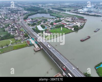 Suzhou. 23 juin 2025. Une photo prise par un drone aérien le 23 juin 2025 montre une vue du pont de Pingwang dans le district de Wujiang de la ville de Suzhou, dans la province du Jiangsu de l'est de la Chine. Les voies de gauche du pont de Pingwang nouvellement construit, un projet de la partie est du projet d'amélioration du canal de navigation de Chang-Hu-Shen (Changxin-Huzhou-Shanghai) (section Jiangsu), ont été officiellement ouvertes à la circulation lundi. Crédit : Ji Chunpeng/Xinhua/Alamy Live News Banque D'Images